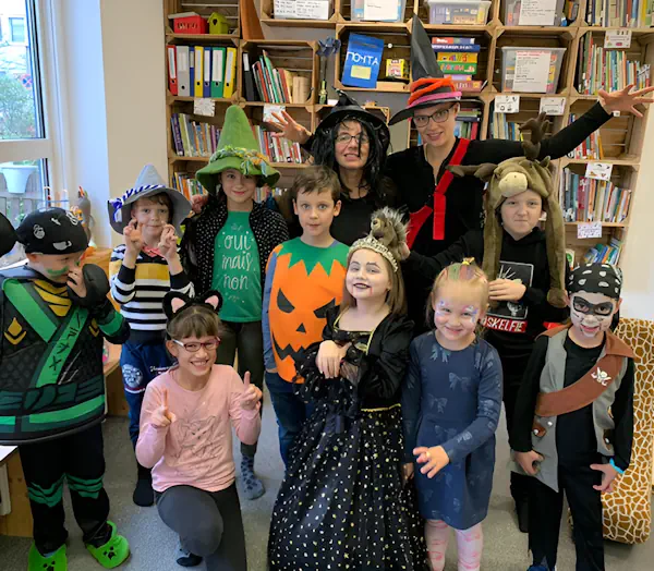 Групповая фотография детей и двух руководителей в игровой комнате. Все одеты в костюмы Helloween.