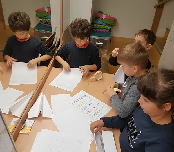 Группа детей сидит за письменным столом и выполняют задания в рабочих листах.