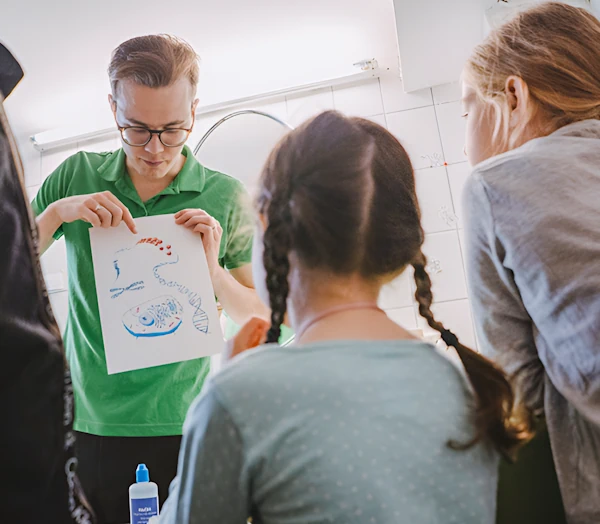 Педагог показывает и объясняет детям рисунок генов, хромосом и ДНК человека.