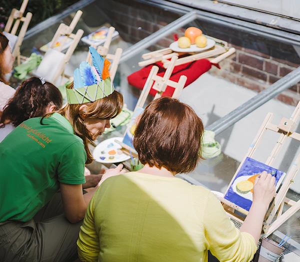 Женщины на художественном мастер-классе рисуют акрилом авокадо на улице.